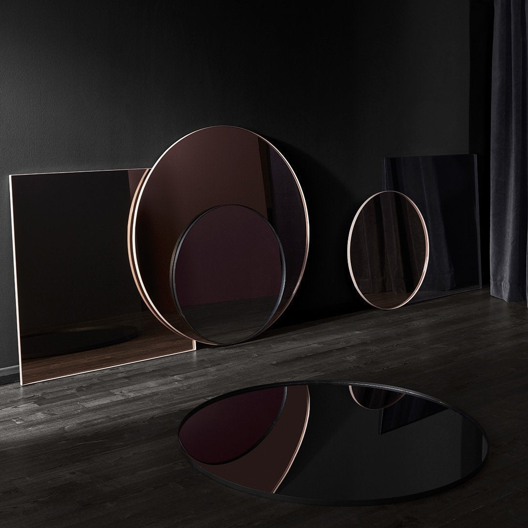 Elegant circular mirrors in deep burgundy and black, framed in sleek metallic tones, showcasing modern minimalist patterns.