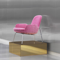 "Stylish pink velvet chair with sleek metallic legs on a modern gold display pedestal."