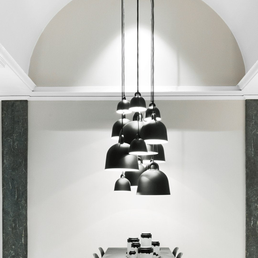 Sleek black pendant lamps with varying sizes, hanging against a minimalist white and gray backdrop.