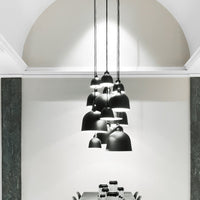 Sleek black pendant lamps with varying sizes, hanging against a minimalist white and gray backdrop.