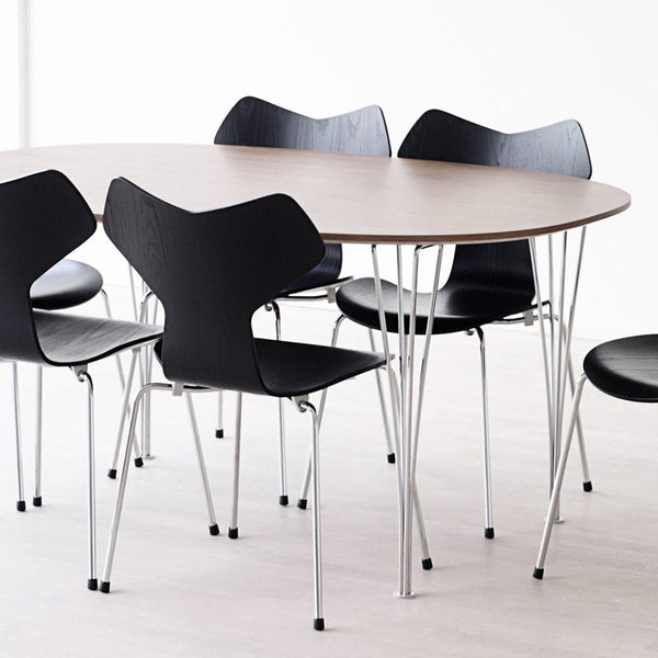 Modern oval table with a natural wood top and six black chairs featuring unique curved backs and sleek silver legs.