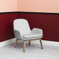 Light gray chair with wooden legs against a backdrop of peach and burgundy walls, accented by a black stripe.