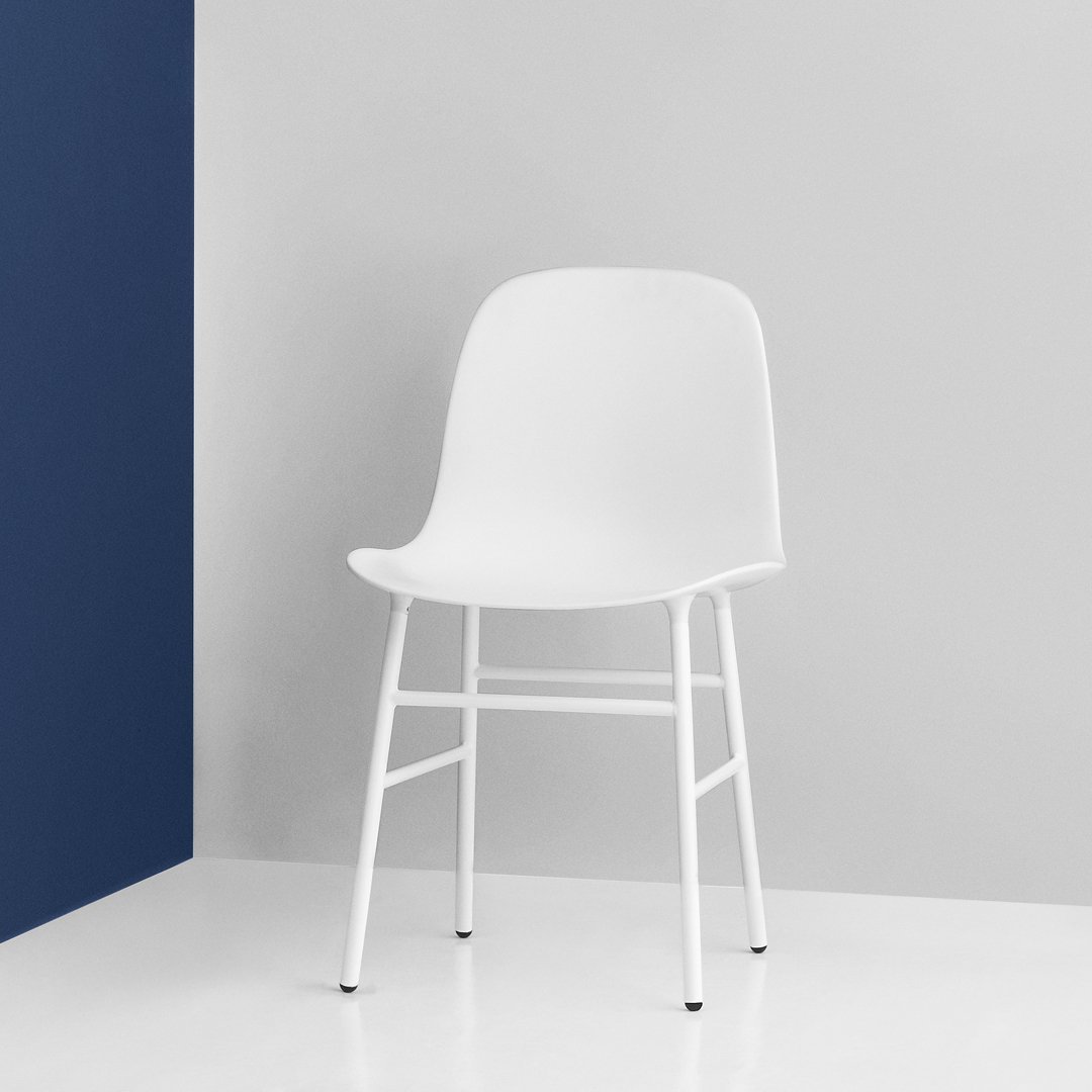 White modern chair against a gray and navy backdrop, featuring a sleek, minimal design and smooth surfaces.