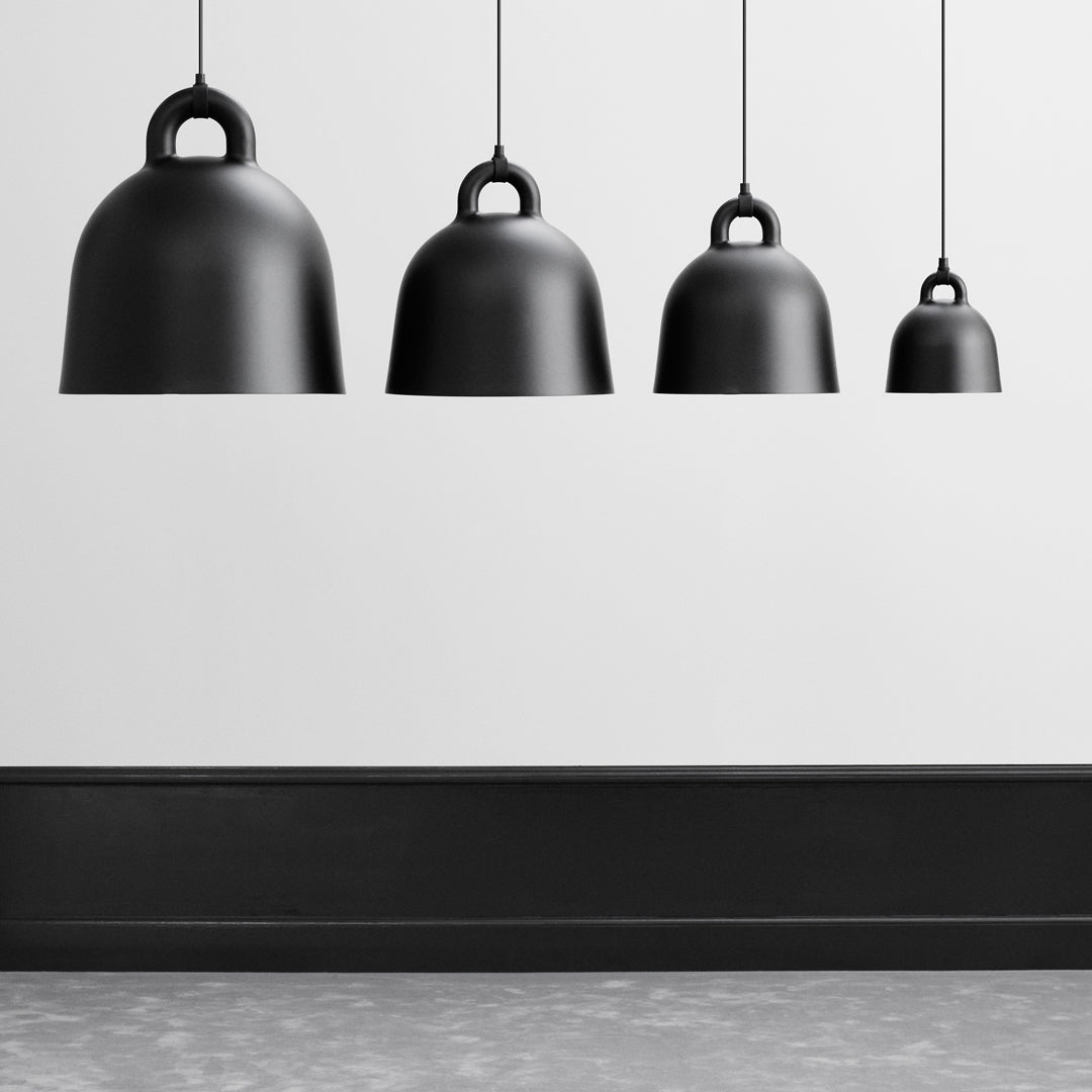 Four black metallic pendant lights of varying sizes, arranged in a modern, minimalist style against a light gray background.