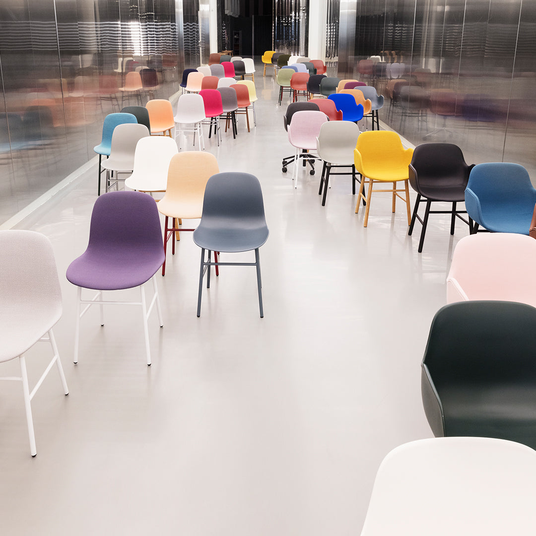 Colorful chairs in pastel, bold, and neutral tones arranged in a modern, sleek setting with a shiny surface.