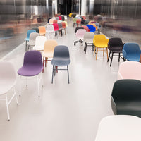 Colorful chairs in pastel, bold, and neutral tones arranged in a modern, sleek setting with a shiny surface.