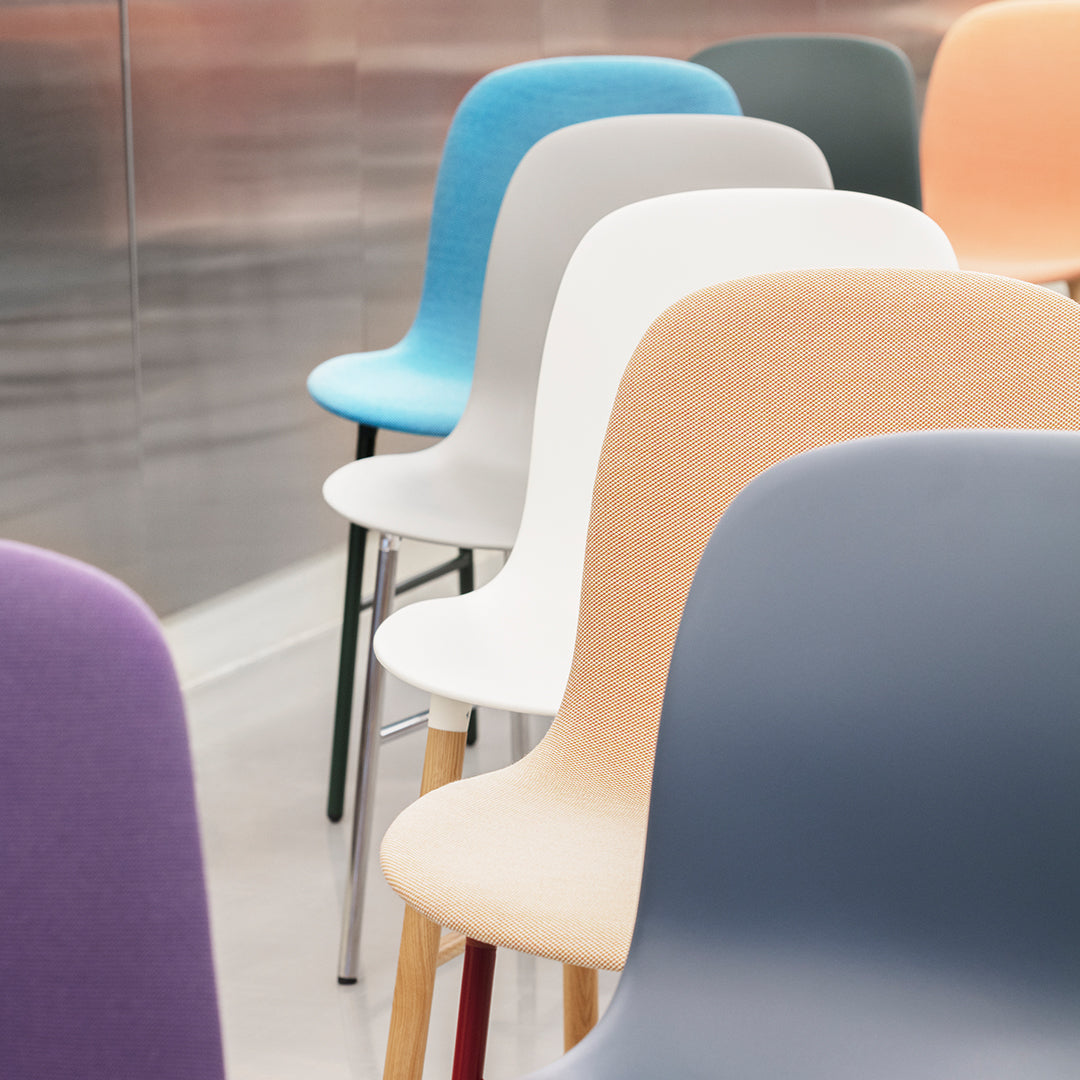 Colorful modern chairs in pastel shades of blue, white, peach, grey, and purple, arranged in a stylish row.