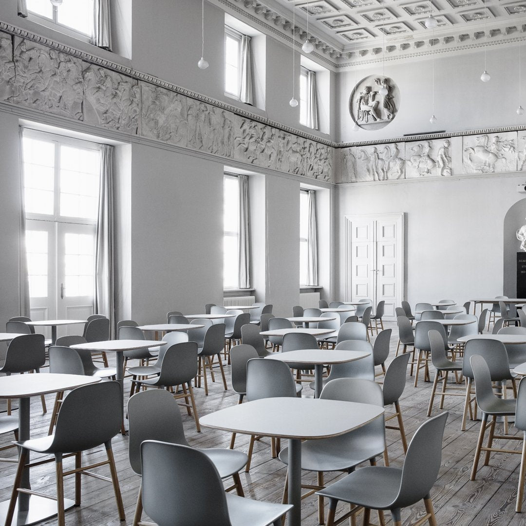 Modern gray chairs and tables in a minimalist, light-filled room with white walls and wooden floors.