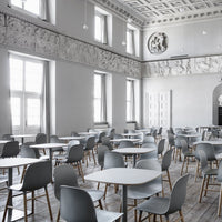 Modern gray chairs and tables in a minimalist, light-filled room with white walls and wooden floors.