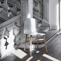Light gray chair with minimalist design, set against a backdrop of white stair railings and wooden flooring.
