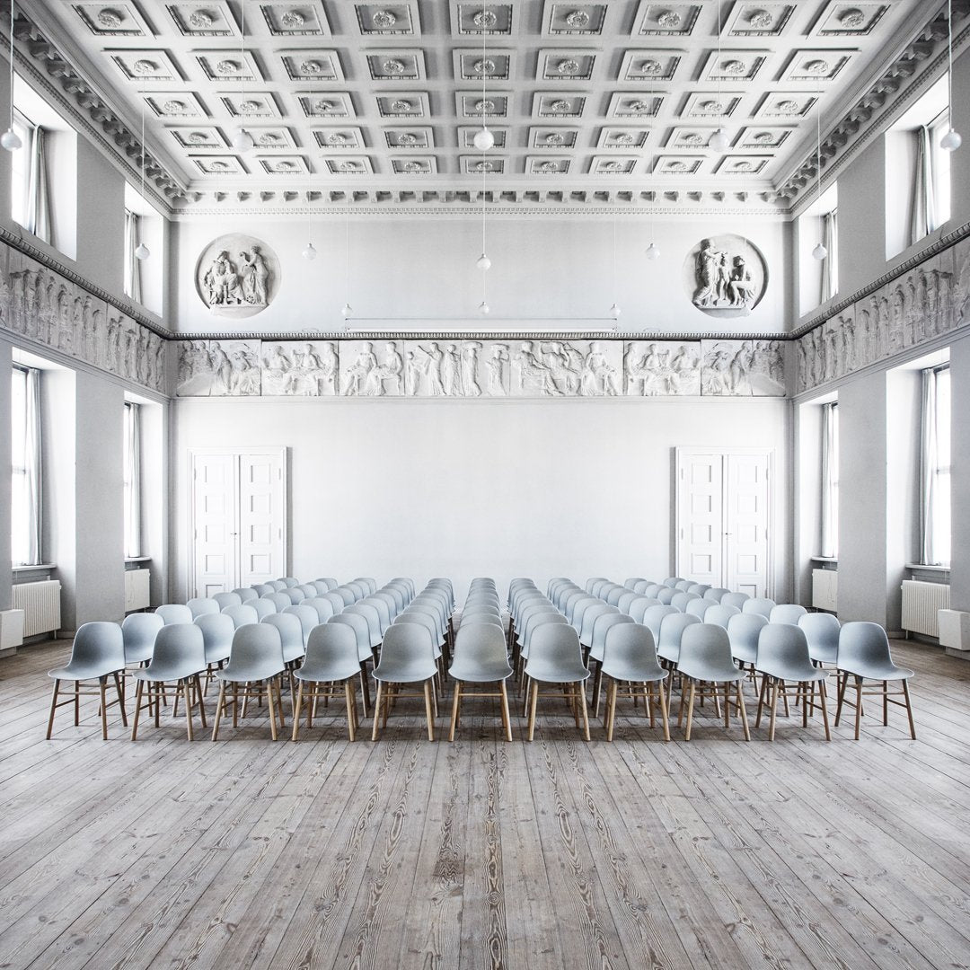Light blue chairs with natural wood legs arranged in a minimalistic, elegant indoor setting with a white ceiling.