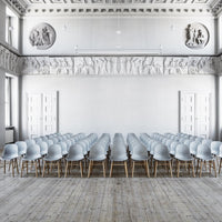 Light gray chairs in a minimalist setting with wooden legs, arranged in neat rows on a wooden floor.