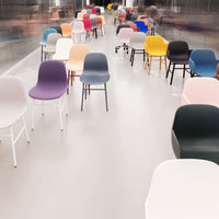 Colorful chairs in various hues including pink, purple, blue, yellow, and black arranged in modern patterns.