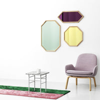 Colorful geometric mirrors in green, purple, and yellow hues, complemented by a pink rug and modern chair.
