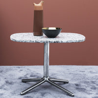 Stylish round table with a speckled white top and sleek silver base, perfect for modern decor.