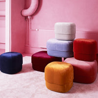 Colorful velvet poufs in vibrant shades of blue, red, yellow, pink, and lavender, showcasing modern patterns.