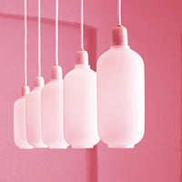 "Five hanging pendant lights in soft pink glass against a matching pink background."