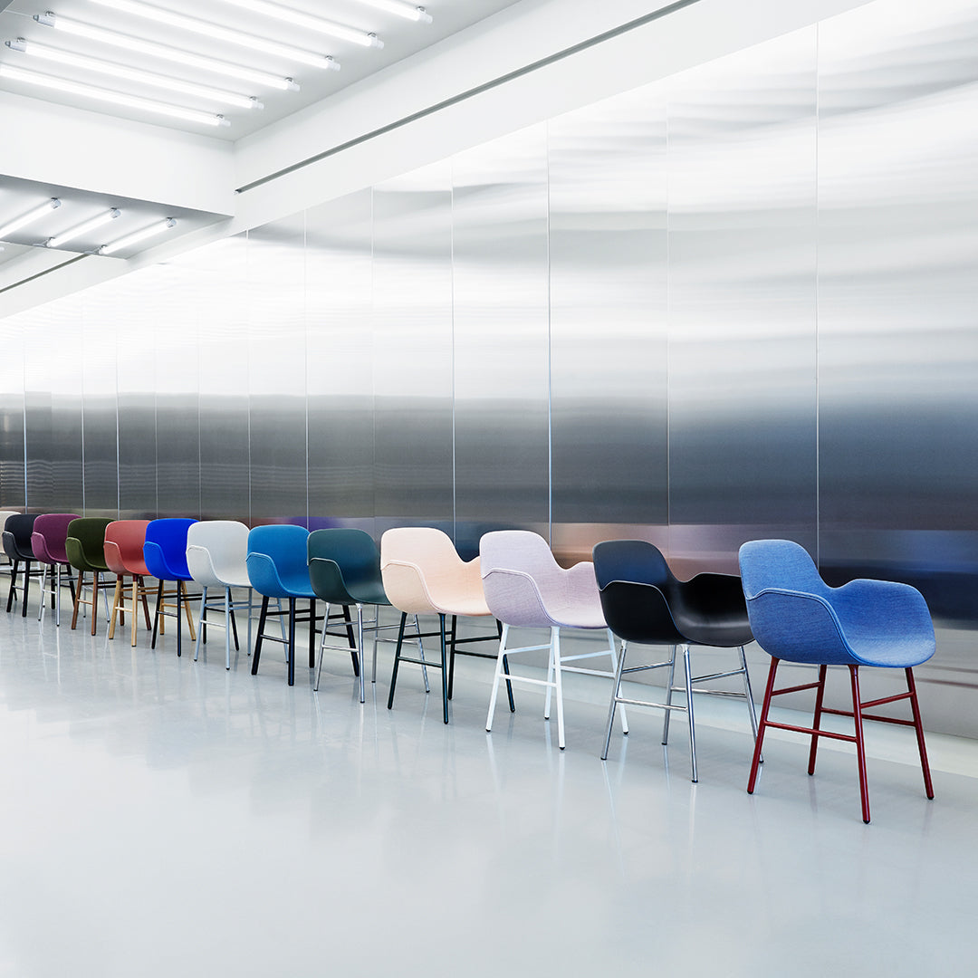 Colorful modern chairs in various shades including blue, pink, purple, black, and red against a sleek metallic backdrop.