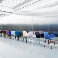 Colorful modern chairs in various shades including blue, pink, purple, black, and red against a sleek metallic backdrop.