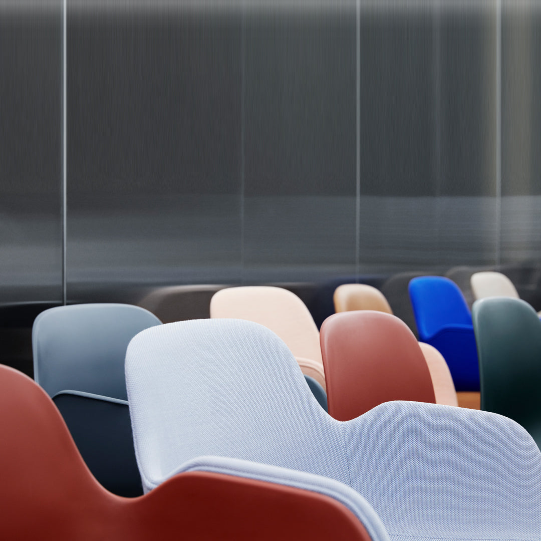 Colorful mix of modern chairs in shades of gray, blue, red, pink, and green with smooth, curved designs.