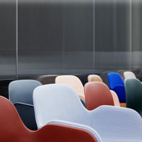 Colorful mix of modern chairs in shades of gray, blue, red, pink, and green with smooth, curved designs.