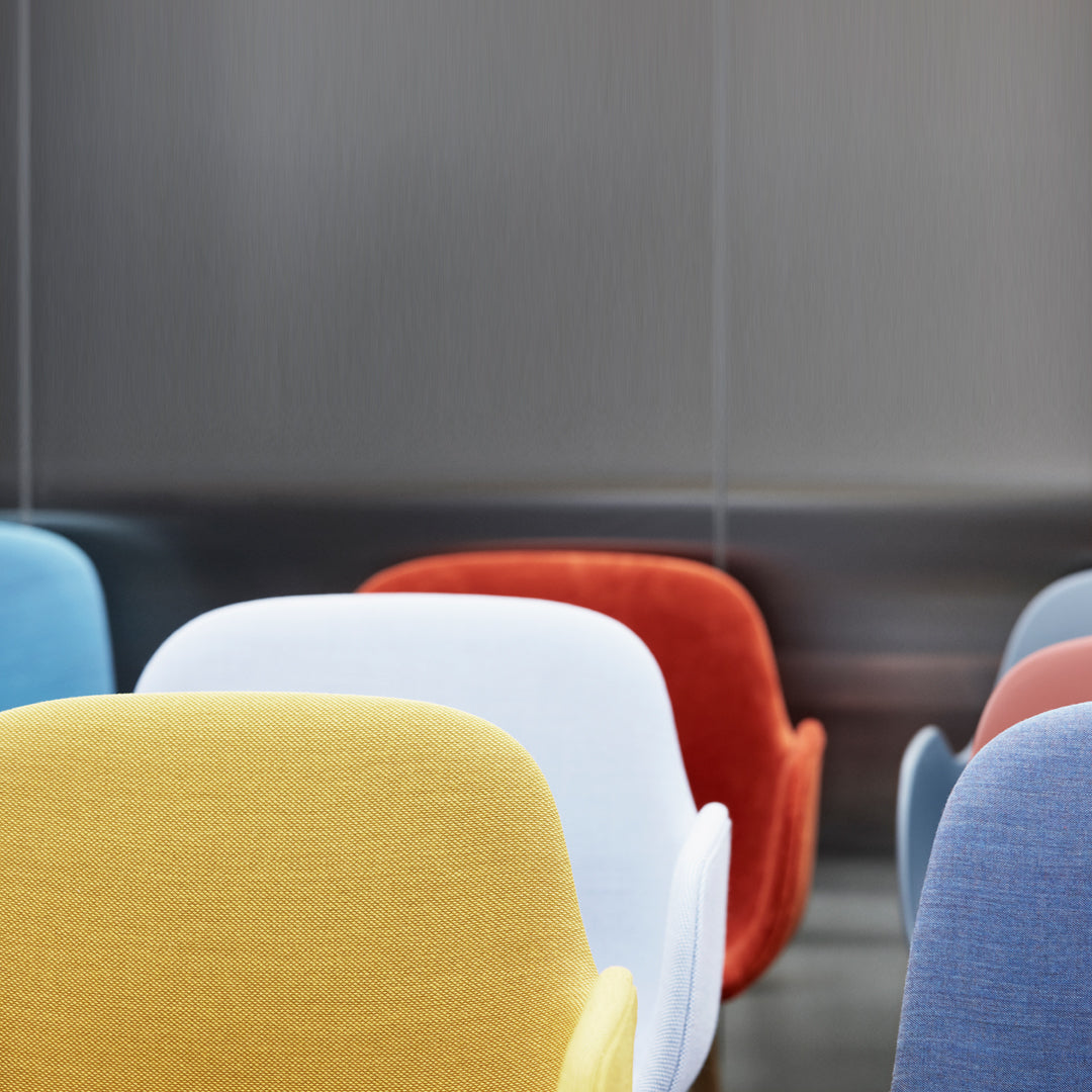 Colorful chairs in pastel shades of yellow, white, blue, red, and grey with textured upholstery.