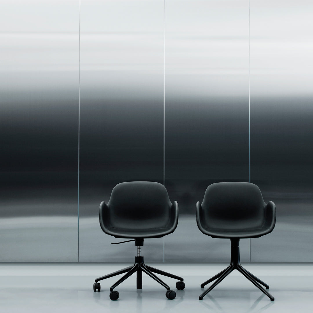 Two modern black office chairs with smooth, curved designs against a sleek, silver gradient background.