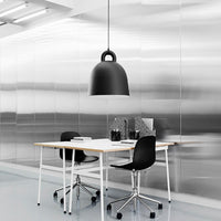 Modern workspace featuring a sleek black lamp, white table, and minimalist black chairs against a metallic silver backdrop.
