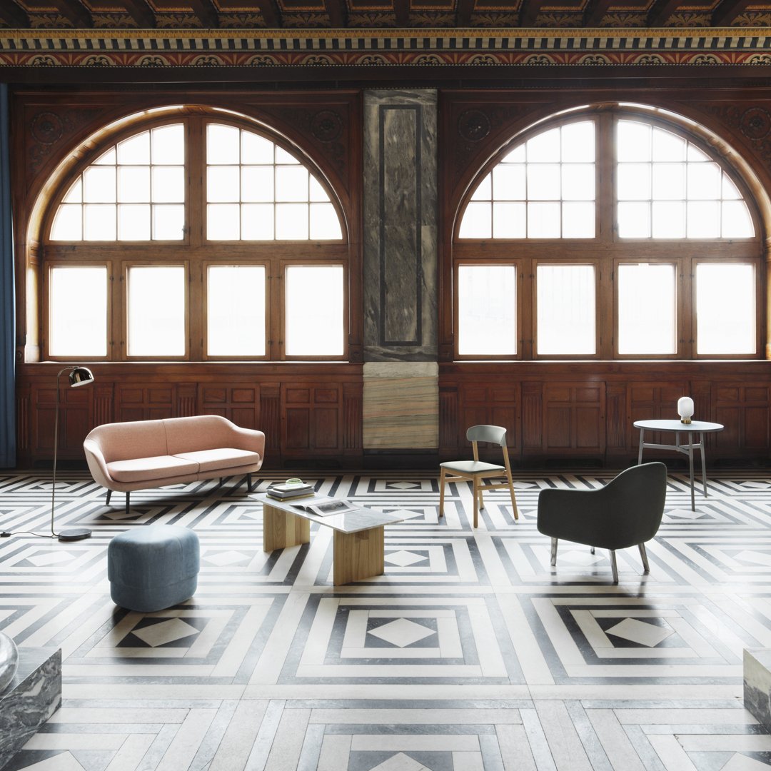 Elegant room with warm wood tones, geometric black and white patterned flooring, and pastel furniture accents.