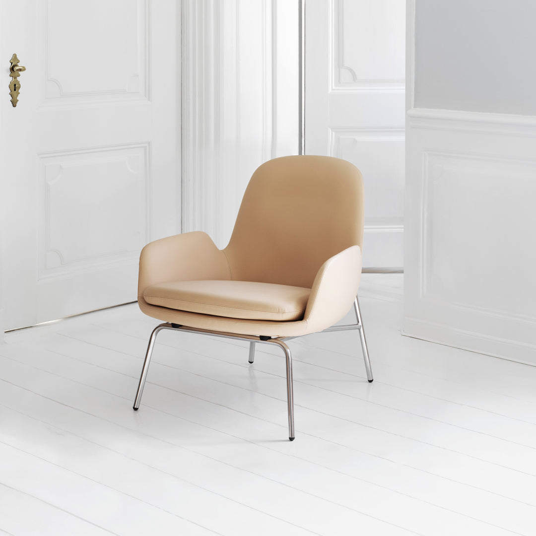 Beige chair with smooth, curved lines and sleek metal legs, set against a minimalist white background.