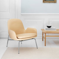 "Light beige chair with smooth contours, paired with a natural wood table and minimalist decor in a bright room."