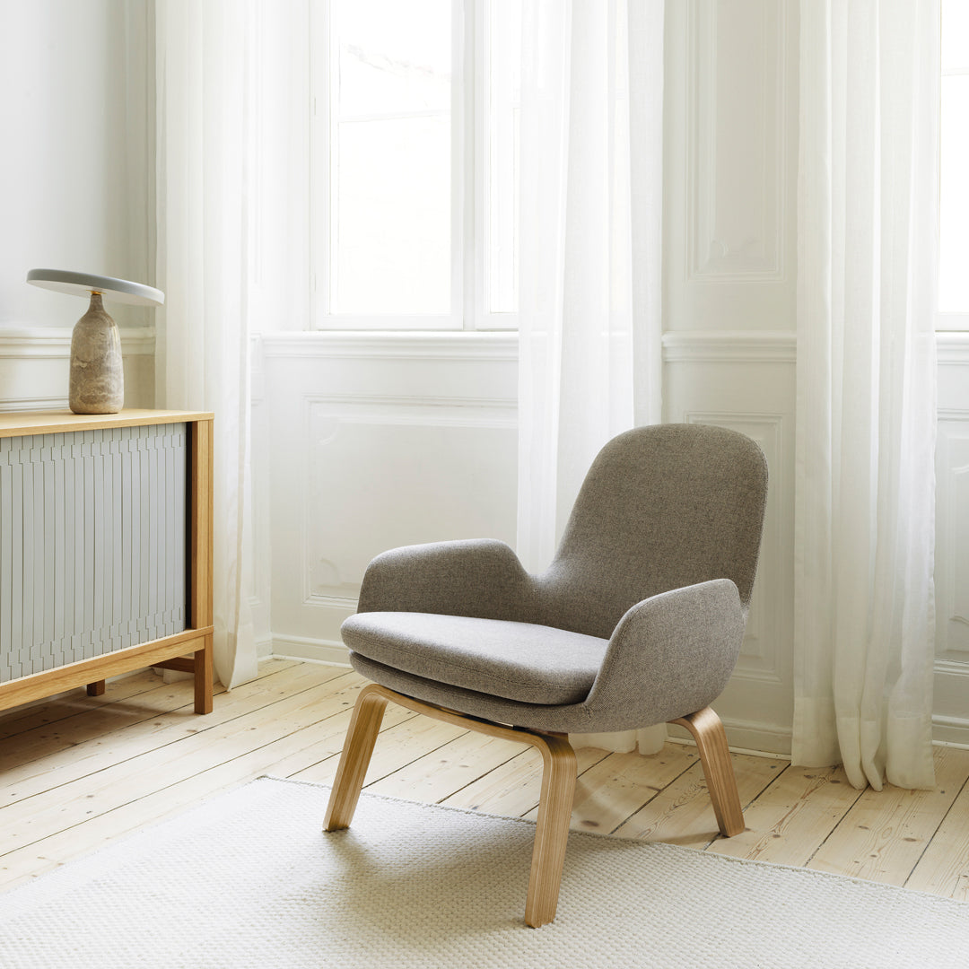 Light gray upholstered chair with a minimalist design, featuring a smooth fabric surface and natural wood legs.