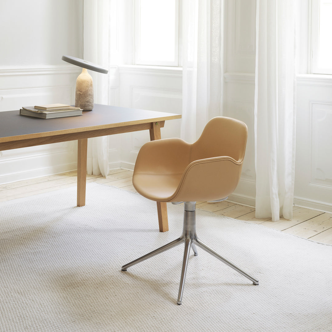 Tan ergonomic chair with a sleek silver base, set against a soft, neutral-toned room with natural light.