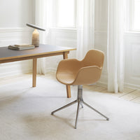 Tan ergonomic chair with a sleek silver base, set against a soft, neutral-toned room with natural light.