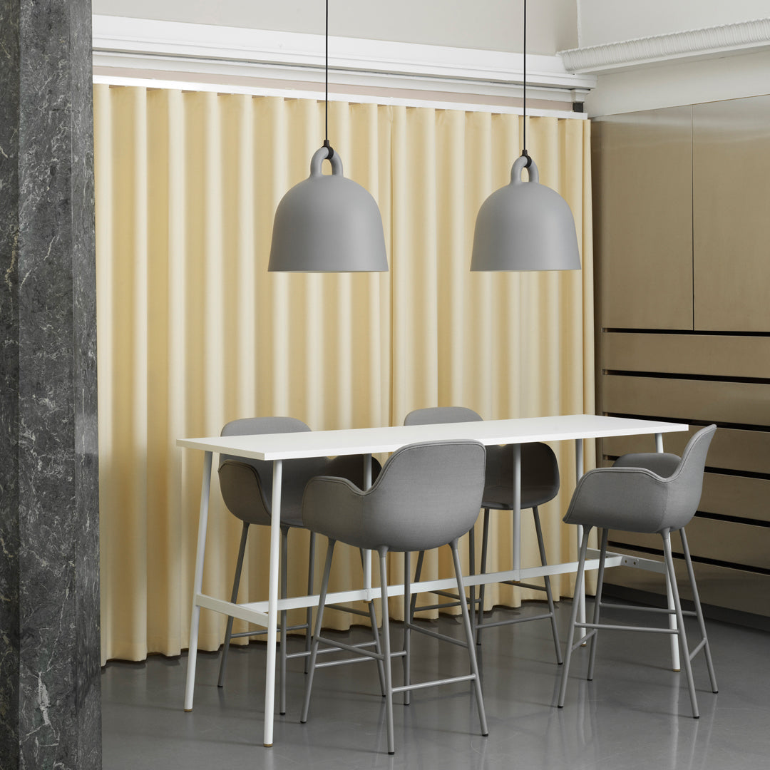 Gray pendant lights and bar stools contrast with a light beige curtain and white table, creating a modern, sleek ambiance.