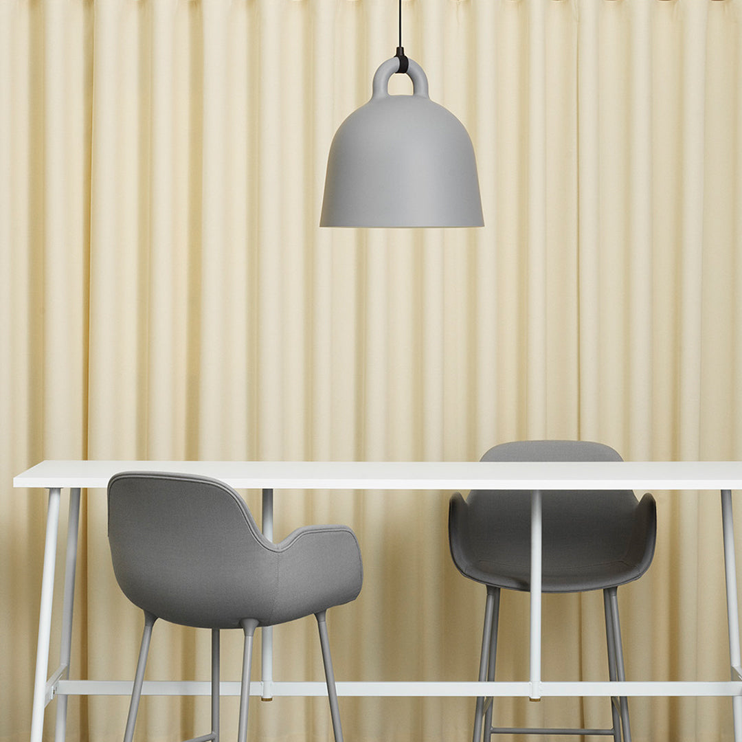 Gray pendant lamp above white table with gray chairs and textured beige curtain backdrop.