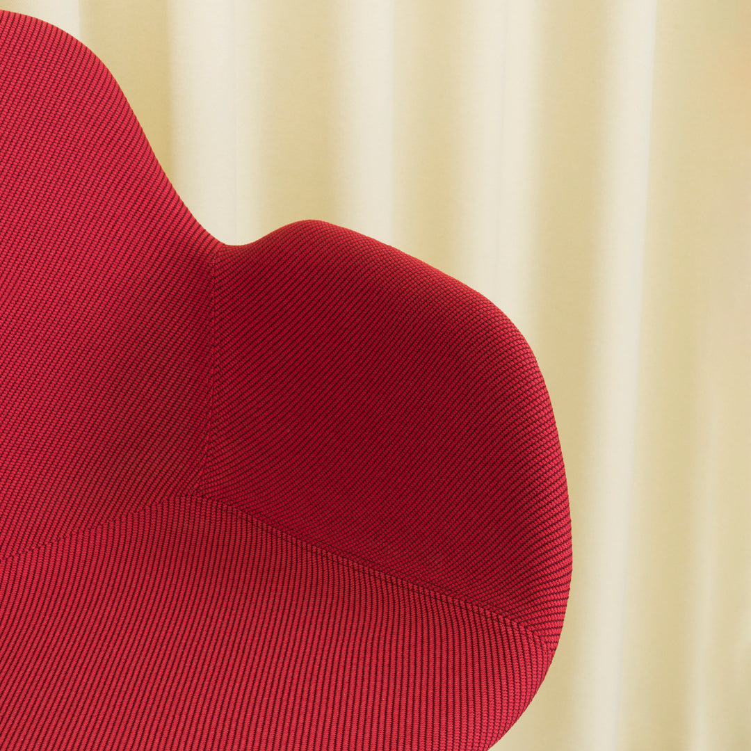 Red ribbed chair against a soft beige backdrop, showcasing bold color contrast and modern texture patterns.