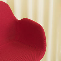 Red ribbed chair against a soft beige backdrop, showcasing bold color contrast and modern texture patterns.