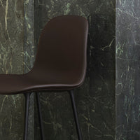 Stylish brown molded chair against a dark green marbled backdrop, highlighting sleek lines and modern design.