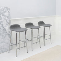 Gray upholstered bar stools with sleek chrome legs, set against a minimalist backdrop of light colors and marble pattern.