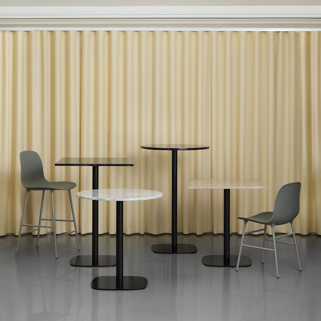 "Modern dining tables in black and white with sleek designs against a soft beige curtain backdrop."