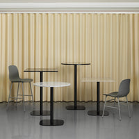 "Modern dining tables in black and white with sleek designs against a soft beige curtain backdrop."