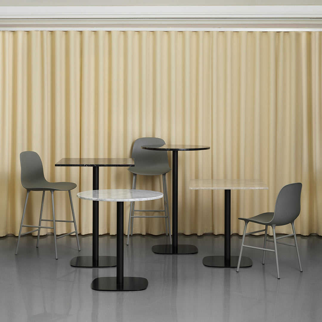 Modern furniture set featuring gray chairs and tables with black bases, against a warm beige curtain backdrop.