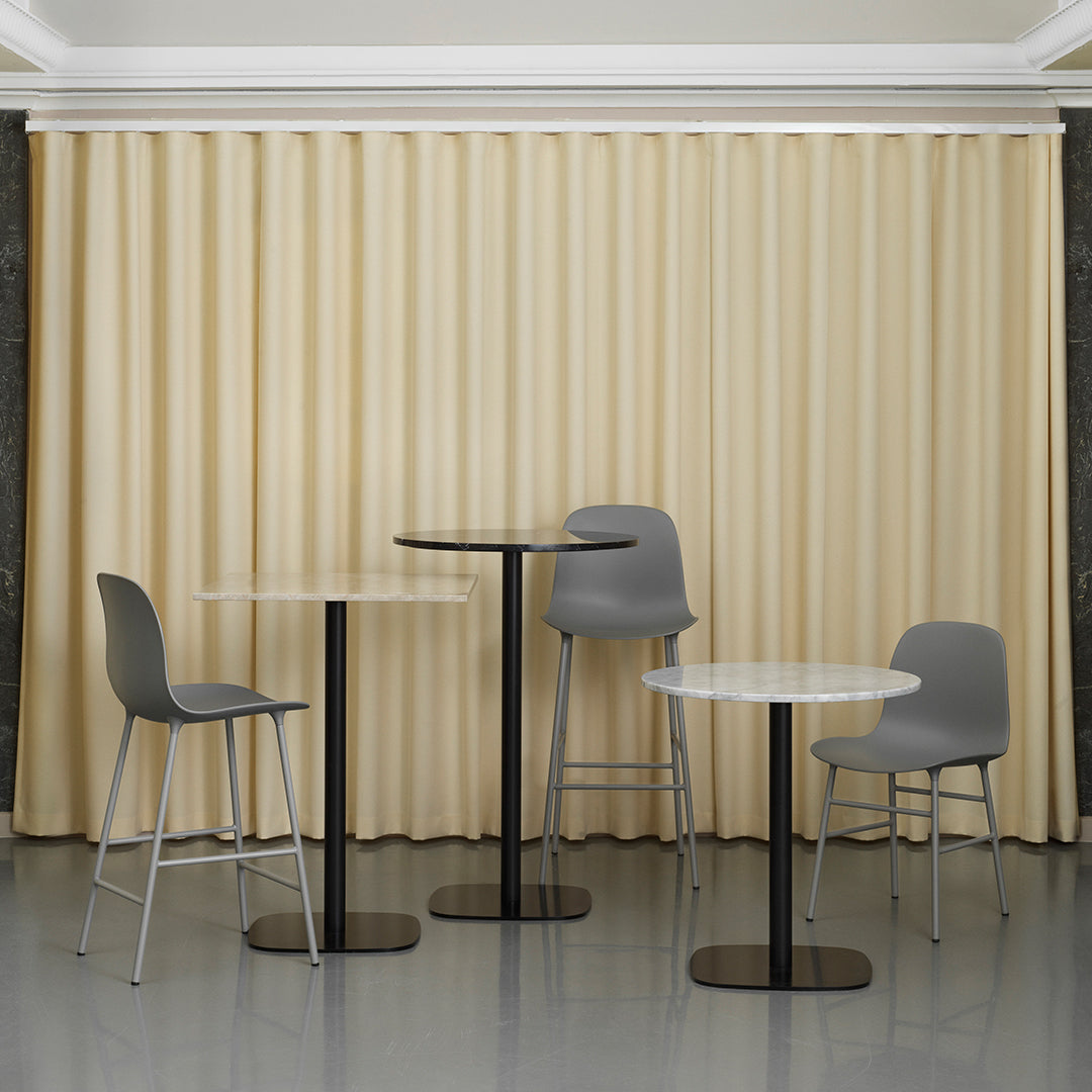 Gray chairs and tables against soft beige curtains with vertical pleats, creating a modern, minimalistic aesthetic.
