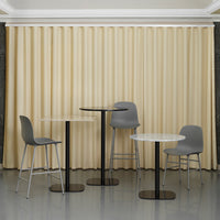 Gray chairs and tables against soft beige curtains with vertical pleats, creating a modern, minimalistic aesthetic.