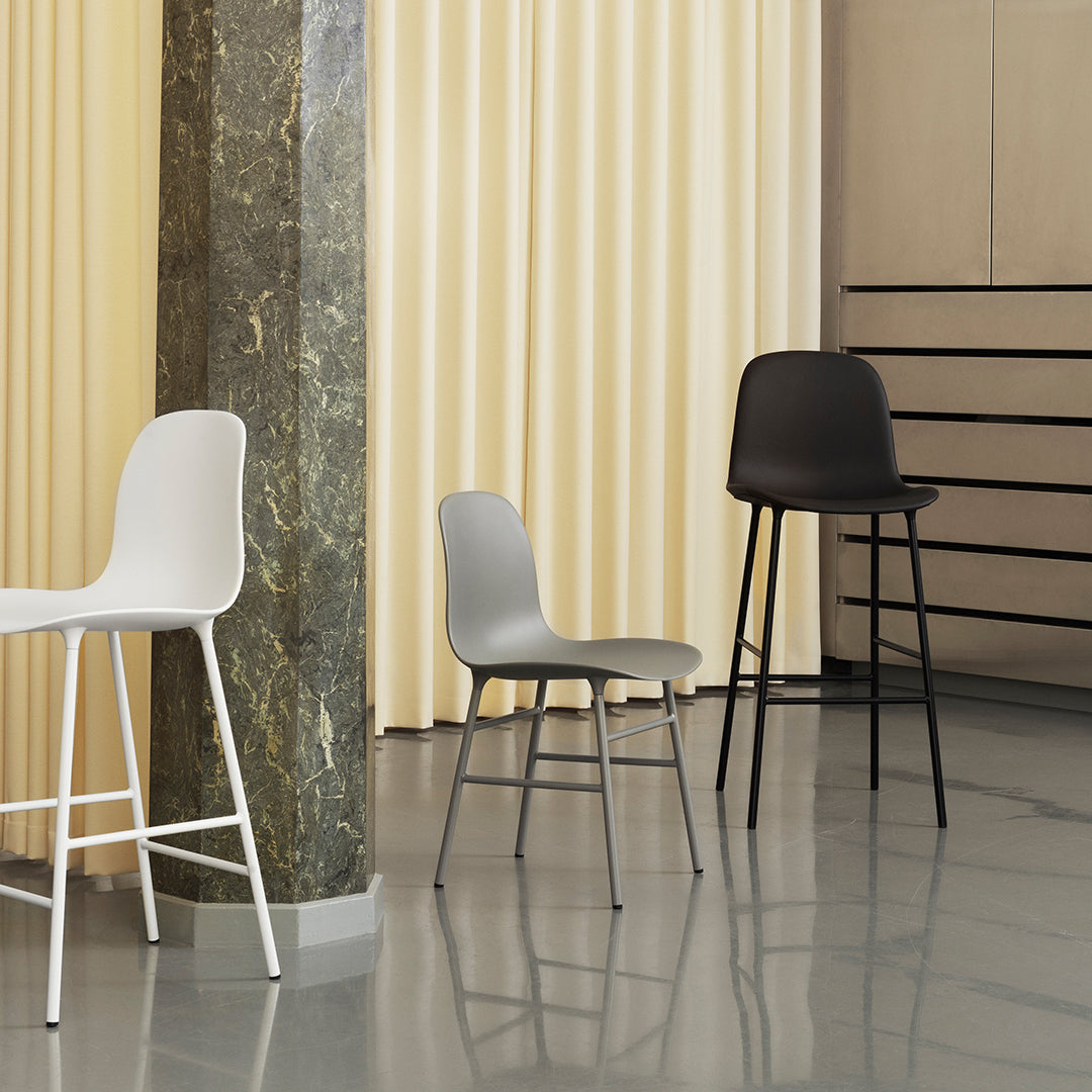 Three modern chairs in white, gray, and black, set against a soft yellow backdrop with sleek lines and textures.
