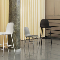 Three modern chairs in white, gray, and black, set against a soft yellow backdrop with sleek lines and textures.