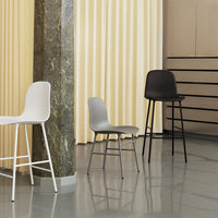 Modern chairs in white, gray, and black against a soft yellow curtain backdrop, showcasing sleek design and minimalist aesthetics.