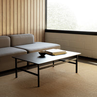 Modern black coffee table with sleek lines, complemented by a neutral gray sofa and warm wooden walls.