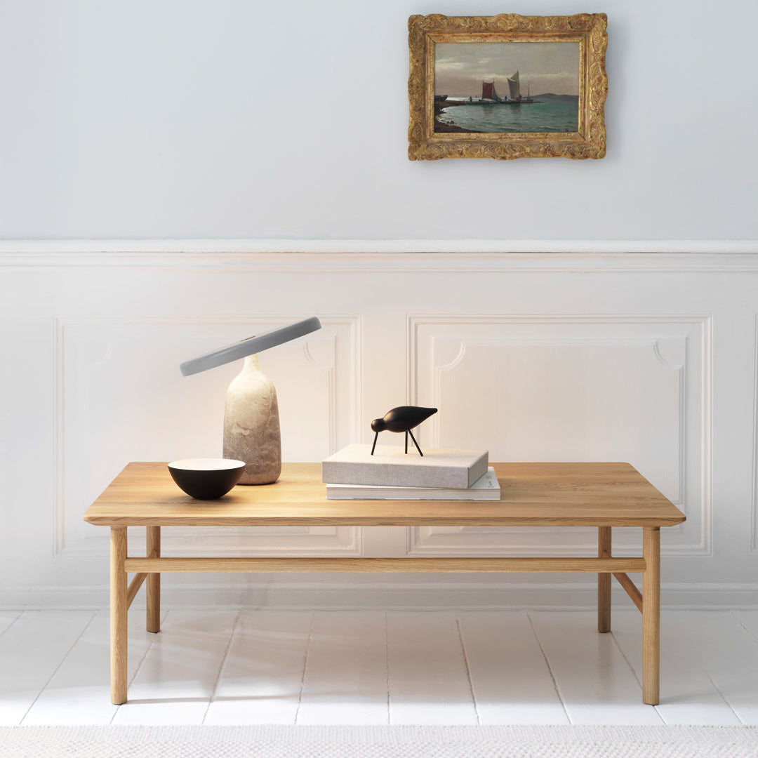 Natural wood coffee table with a smooth finish, featuring minimalist design and neutral tones. Stylish decor accents nearby.